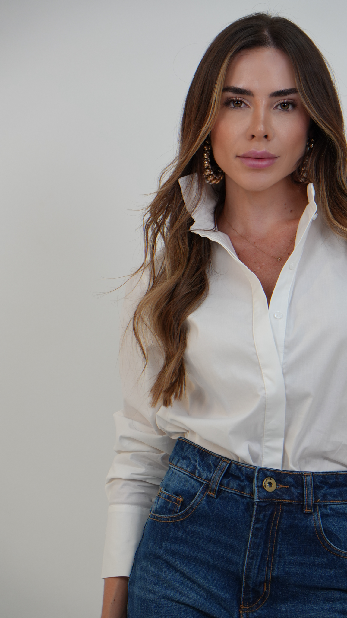 Mãos da curadora analisando peças de roupa.